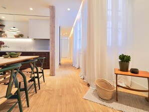 Una cocina moderna con suelo de madera, un comedor con sillas verdes y una isla de cocina.