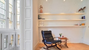 Ein Zimmer mit Holzboden, einem schwarzen Ledersessel, weißen Wänden und einer weißen Tür.