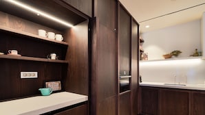 Eine moderne Küche mit dunklen Holzschränken, einer weißen Arbeitsplatte und einem eingebauten Backofen.
