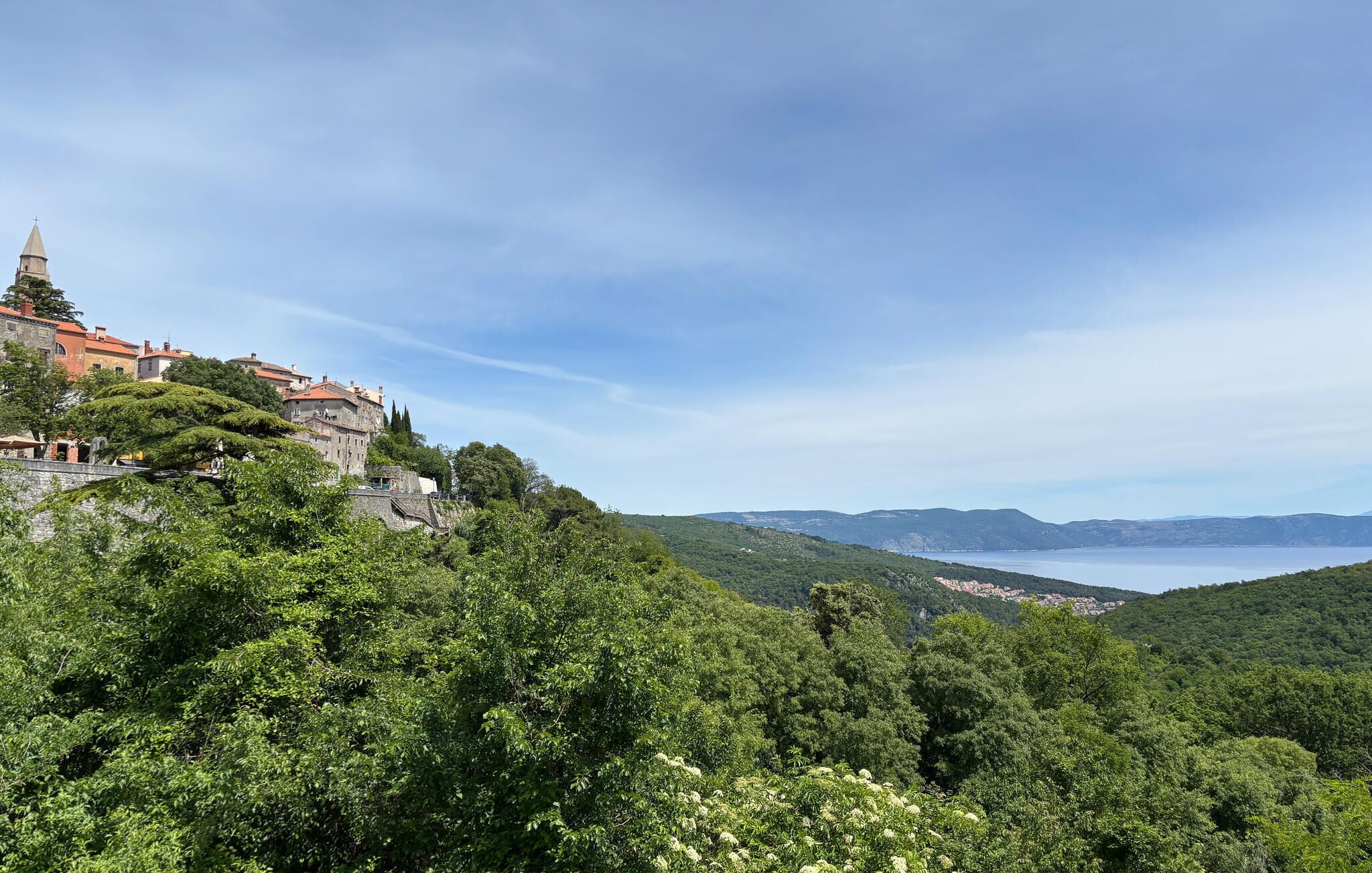 A mountainous landscape with a historic building featuring red-tiled roofs and a prominent tower.