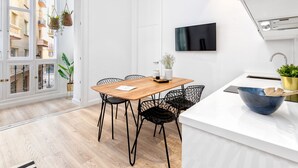 Eine moderne Küche mit einem Holztisch, schwarzen Stuhlgestellen aus Draht, einer weißen Arbeitsplatte und einem eingebauten Ofen.