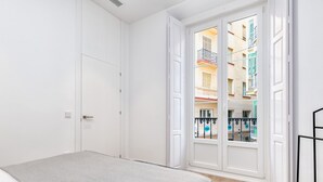 Ein Schlafzimmer mit Bett, einer Tür und Blick auf ein Gebäude mit Balkonen.