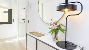 A modern interior with a white console table, a black desk lamp, and a vase with pink flowers. - Central Málaga: Modern 2BR Apartment with Patio, Terrace, and Free Parking (Málaga)