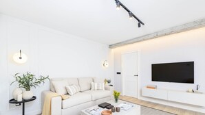 A modern living room with a sofa, coffee table, and a flat-screen TV mounted on the wall. - Central Málaga: Modern 2BR Apartment with Patio, Terrace, and Free Parking (Málaga)