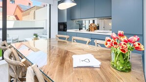 A modern kitchen with a wooden dining table, chairs, and a vase of tulips. - Central Málaga: Modern 2BR Apartment with Patio, Terrace, and Free Parking (Málaga)