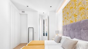 Una habitación de hotel moderna con una cama grande, una mesita de noche con lámpara y un papel tapiz estampado en la pared.