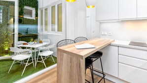 Una cocina moderna con armarios blancos, una isla de madera y un comedor con sillas blancas.