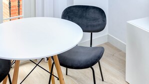 Un comedor moderno con una mesa redonda blanca y dos sillas negras tapizadas con patas de madera.