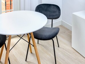 Ein moderner Essbereich mit einem runden weißen Tisch und zwei schwarzen Sesseln mit Holzbeinen.