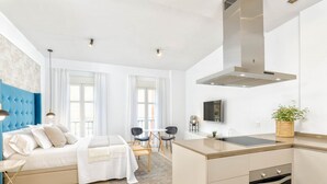 Un apartamento moderno con kitchenette, comedor y dormitorio.