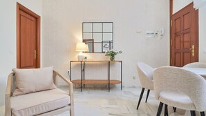 A room with a sofa, a dining table, a lamp, and a mirror on the wall. - Elegant 2-Bedroom Apartment in Central Málaga, Close to Key Attractions (Málaga)