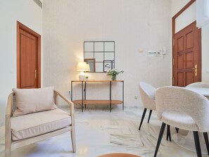 Ein Zimmer mit einer Couch, einem Esstisch, einer Lampe und einem Spiegel an der Wand.