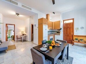 Een moderne keuken met houten kastjes, een zithoek met een ontbijttafel en een woonkamer met een bank en salontafel.
