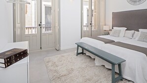 Una camera da letto con un letto grande, una panca, un comodino e una ventola a muro.
