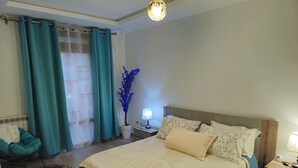 Une chambre à coucher comprenant un lit, des tables de chevet, une lampe, une chaise et une plante décorative.