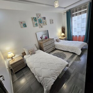 Una habitació amb dos llits, un aparador, un mirall i obra d'art a la paret.