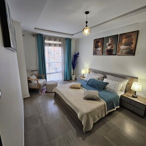A bedroom with a large bed, bedside tables, a window with curtains, and wall art.