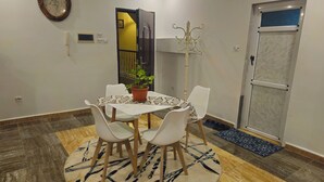 Un espace repas comprenant une table, des chaises, une plante en pot et un tapis à motifs.
