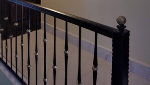 Un escalier avec une balustrade noire menant à une pièce dotée d’une porte en bois et d’une œuvre d’art accrochée au mur.