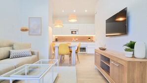 Een moderne woonkamer met een bank, salontafel en een aan de muur bevestigde televisie.