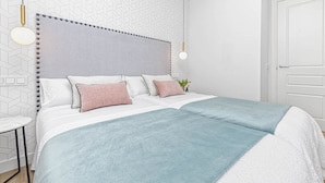 A modern bedroom with a large bed, a bedside table, and a wall-mounted light fixture. - Charming Apartment Near Alcazaba Málaga with Modern Amenities, WiFi, and A/C (Málaga)