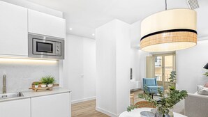 A modern kitchen with white cabinetry, a built-in microwave, and a dining area with a round table and chairs. - Charming Apartment Near Alcazaba Málaga with Modern Amenities, WiFi, and A/C (Málaga)