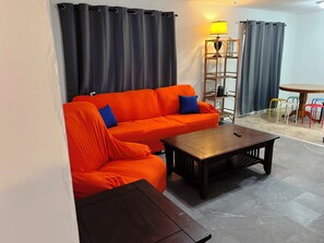 Un salon comprenant un canapé, une table basse, une lampe et une table à manger avec des chaises.