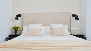Una cama bien hecha, con un cabecero color beige y dos lámparas de noche.