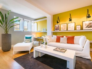 A modern living room with a white sofa, a coffee table, and a large potted plant. - Elegant 3-Bedroom Apartment in Malaga City Center, Ideal for Families or Friends (Málaga)