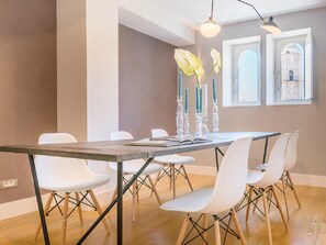 A dining area with a wooden table, white chairs, and a vase with candles. - Elegant 3-Bedroom Apartment in Malaga City Center, Ideal for Families or Friends (Málaga)