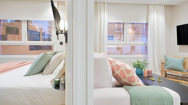 Ein modernes Schlafzimmer mit einem Bett, einem Nachttisch und einem Fenster mit Vorhängen.