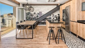 Een moderne keuken met houten kastjes, een roestvrijstalen koelkast en een eethoek met een houten tafel en stoelen.