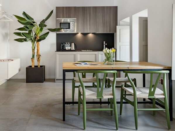 Une cuisine moderne équipée d’un four à micro-ondes encastré, d’une machine à café et d’un vase rempli de fleurs posé sur le plan de travail.