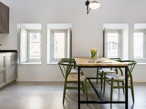 Une cuisine moderne avec une table à manger, des chaises vertes et un vase de fleurs.