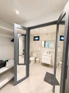 Un bagno moderno con servizi igienici, lavabo e specchio, e zona doccia con porta in vetro.
