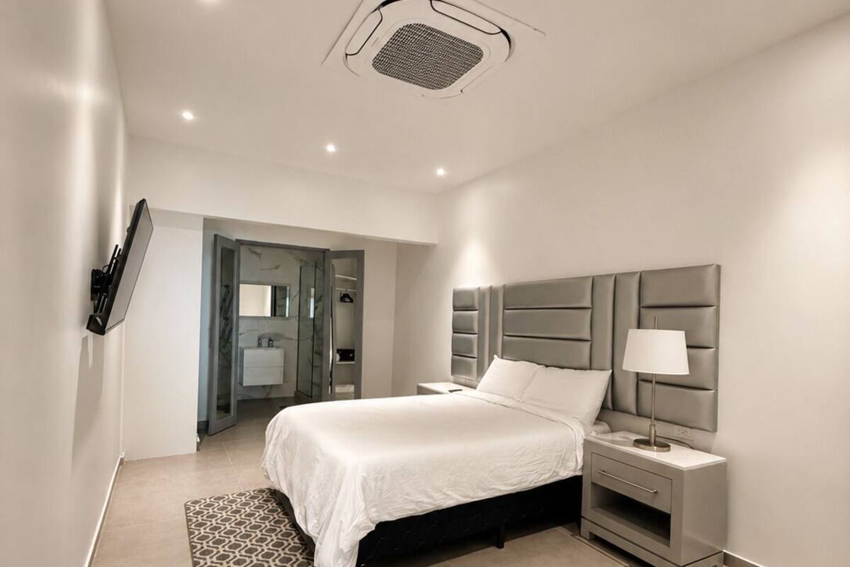 Een moderne slaapkamer met een bed, nachtkastje en een ingebouwde televisie.
