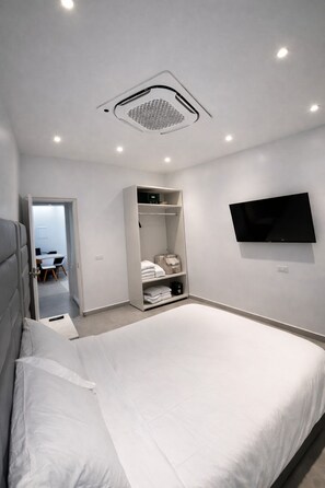 Camera da letto moderna con un letto grande, un armadio a muro, una TV montata a parete e una bocchetta di ventilazione al soffitto.