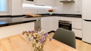 Une cuisine moderne avec des meubles blancs, un four à micro-ondes, une cuisinière et un évier.
