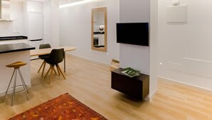 Une cuisine moderne avec un coin repas, un téléviseur à écran plat fixé au mur et une petite table d’appoint avec un magazine.