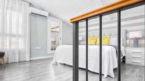 Een moderne slaapkamer met een bed, nachtkastjes, een raam met gordijnen en een airconditioning.