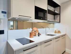 A modern kitchen with a built-in stove, two sinks, and a wooden spice rack. - Studio près de La Malagueta avec WiFi et climatisation, à deux pas du port et musée Pompidou (Málaga)