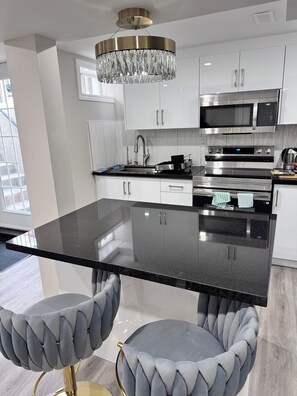 A modern kitchen with a central island, stainless steel appliances, and a chandelier. - Perfect Location: Warm, Charming Basement (Mississauga)