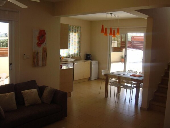 A compact living space with a kitchenette, dining area, and a staircase. - Athena Villa (Ayia Napa)