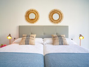 A double bed with two pillows, a grey headboard, and two wall-mounted circular mirrors. - Central Málaga Apartment with Balcony, 2 Bedrooms & Modern Amenities (Málaga)