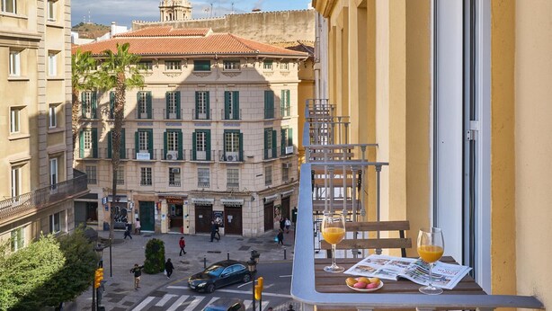 Un balcon, un journal, un verre de jus d’orange et un verre de vin.