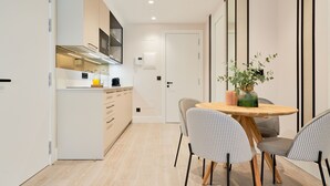 Een moderne keuken met een centraal eiland, een eetgedeelte met een houten tafel en gestreept beklede stoelen, en een minimalistische inrichting.
