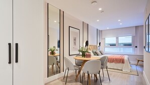 A modern bedroom with a large bed, bedside tables, a desk with chairs, and a window with a view. - Comfortable studio in La Malagueta with air conditioning and WiFi, near Malaga port (Málaga)