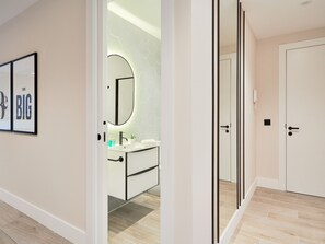 Ein modernes Badezimmer mit einem weißen Waschtisch, einem runden Spiegel und einer Rückwand aus sechseckigen Fliesen.