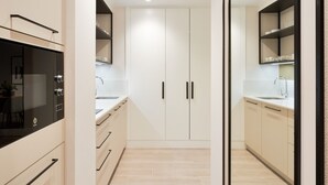 A modern kitchen with white cabinetry, a black oven, and a glass door. - Comfortable studio in La Malagueta with air conditioning and WiFi, near Malaga port (Málaga)