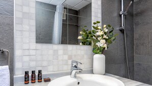 Ein modernes Badezimmer mit einem weißen Waschbecken, einem Spiegel und einer Dusche.